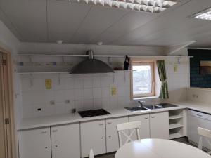 una cucina con armadi bianchi, lavandino e piano cottura di De Maretak a Meetkerke
