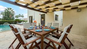 a dining room table with chairs and a table and a pool at Villa Camelot by Ezoria Villas in Coral Bay