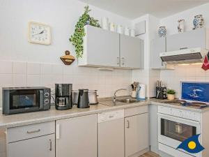 班辛海的住宿－Ostseepark 12 Whg 02，厨房配有白色橱柜和微波炉