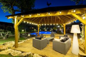 a wooden deck with a pergola at night at Hotel Village Motel in Tournus