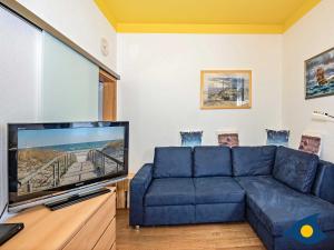 Una sala de estar con un sofá azul y un televisor de pantalla plana. en Residenz Bellevue Whg 13, en Bansin