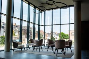 a group of chairs and tables in a room with windows at in2 the Boardinghouse in Übach-Palenberg