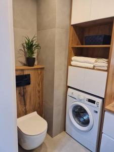 a bathroom with a washing machine and a toilet at Bastion Apartament in Gdańsk