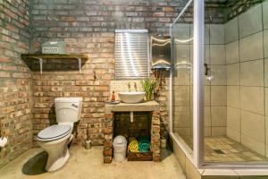 a brick bathroom with a toilet and a shower at Schoemanshoek Glamping in Oudtshoorn