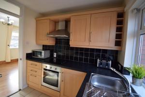 een keuken met houten kasten en een kookplaat met oven bij Prime Location Apartment in Belfast +13 foto's