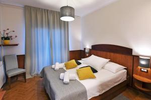 a bedroom with a bed with yellow and white pillows at Hotel Stanger in Lovran