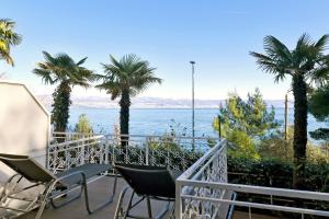 a balcony with chairs and palm trees and the ocean at Hotel Stanger in Lovran