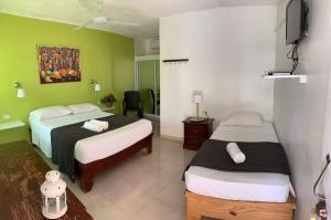 a hotel room with two beds and a television at Hotel Pedernales Italia Republica Dominicana in Pedernales