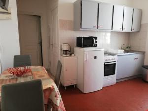 eine Küche mit weißen Schränken, einem Tisch und einer Mikrowelle in der Unterkunft Appartement Le Cernuschi 2C in Menton