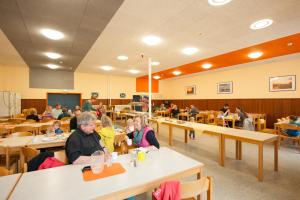 un grupo de personas sentadas en mesas en un aula en Jugendherberge Cuxhaven, en Cuxhaven