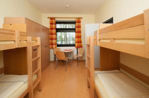 a dorm room with bunk beds and a table at Jugendherberge Cuxhaven in Cuxhaven