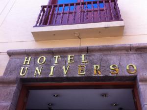 un cartel que lee la universidad del hotel al lado de un edificio en Hotel Universo, en Ayacucho