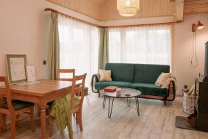 a living room with a green couch and a table at Zielony domek nad Marychą w Budwieć in Stanowisko