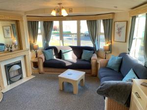 a living room with a blue couch and a fireplace at Lovely Static Holiday Caravan near Whithorn in Whithorn