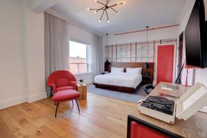 um quarto de hotel com uma cama e uma cadeira vermelha em The Walper Hotel, part of JdV by Hyatt em Kitchener