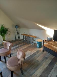 een woonkamer met 2 stoelen en een tafel bij Aux p'tits bonheurs la grange in Neuve-Chapelle