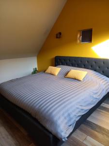 uma cama grande num quarto com uma parede amarela em Aux p'tits bonheurs la grange em Neuve-Chapelle