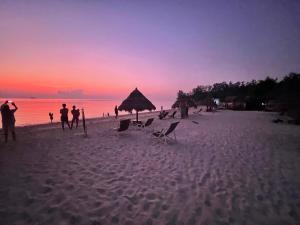 a group of people on the beach at sunset at Nice Sea Resort in Srithanu