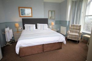 a bedroom with a large bed and a chair at Leahurst Bed and Breakfast in Tywyn