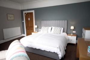 1 dormitorio con 1 cama grande con sábanas blancas en Leahurst Bed and Breakfast en Tywyn