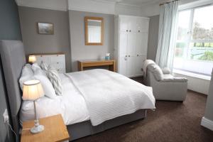 a bedroom with a bed and a chair and a window at Leahurst Bed and Breakfast in Tywyn