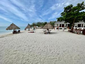 a beach with umbrellas and people laying on the sand at Nice Sea Resort in Srithanu