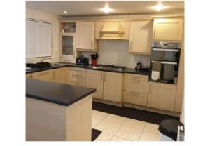 a kitchen with white cabinets and a black counter top at Stunning 4-Bed House in Walsall in Walsall