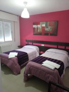 two beds in a room with pink walls at O novo alto do couso in Ourense
