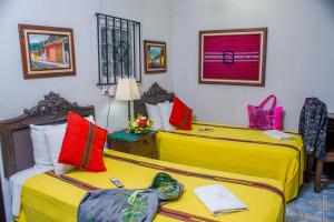 2 camas en una habitación de hotel con almohadas amarillas y rojas en Hotel Casa Rustica by AHS, en Antigua Guatemala