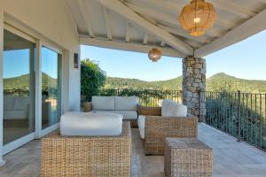 patio con sofá y sillas en el balcón en Villa Gelsomino a soli 500 mt dal mare con piscina privata e vista mare, en Castiadas