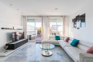 sala de estar blanca con sofá y TV en Luxury Duplex 200 M2 Terrace Parking StayInSeville en Sevilla