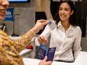 Una mujer tiene una tarjeta de crédito. en ibis budget Bordeaux Centre Mériadeck en Burdeos