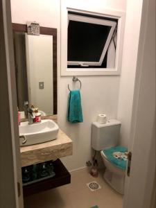 y baño con lavabo, aseo y espejo. en Apartamento em Capão da Canoa beira mar, en Capão da Canoa