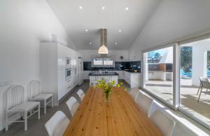 a kitchen with a wooden table and white chairs at Villa Son Blanc Grupo Seranova Luxury Hotel in Sa Caleta