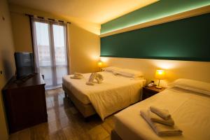 モンティキアーリにあるHotel Elefanteのベッド2台、薄型テレビが備わるホテルルームです。