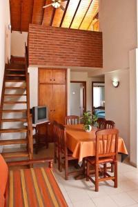 a dining room with a table with chairs and a staircase at Complejo de Mar Wasiyki Villa Gesell in Villa Gesell