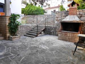 an outdoor patio with a stone fireplace and stairs at Apartments Vrsalovic in Bol