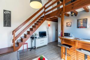 a living room with a staircase with a desk and a television at DUPLEX DESIGN TERRASSE - Parking in Mont-de-Marsan