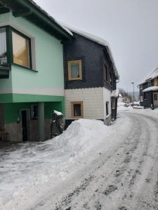 una calle cubierta de nieve frente a una casa en Ferienwohnung Zur alten Bäckerei, en Frauenwald