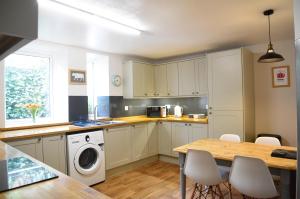 a kitchen with a table and a washing machine at Lower Flat Hillhouse in Portree