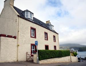 a white building with a black roof at Lower Flat Hillhouse in Portree