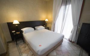 1 cama blanca grande en una habitación con ventana en Palmeraie Village, en Marrakech