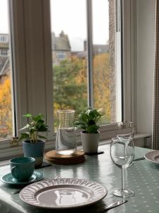 una mesa con un plato y gafas y una ventana en Peebles Cottage Apartment with River View and Bike Store en Peebles