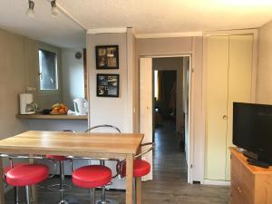 a kitchen with a table with red chairs and a television at Appartement Station de ski - Les Agudes - 6 pers in Gouaux-de-Larboust