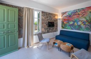 a living room with a blue couch and a painting at Villa Cerise by Upgreat Hospitality in Egina