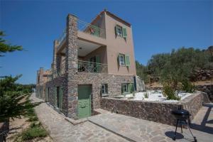 a house with a green door and a stone wall at Villa Cerise by Upgreat Hospitality in Aegina Town