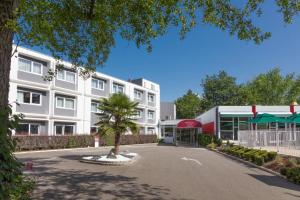 un edificio de apartamentos con una palmera en la entrada en Mercure Strasbourg Aéroport, en Ostwald