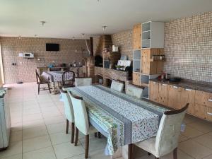 a dining room with a table and chairs and a kitchen at Sitio Bom Retiro in São Pedro da Aldeia