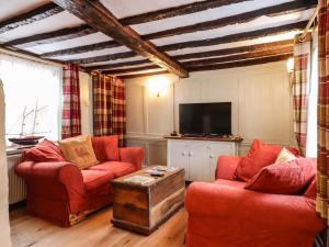 a living room with two red couches and a tv at Driftwood Cottage in Harwich