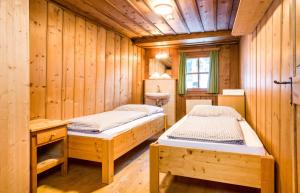 two beds in a room with wooden walls at Stern LODGE im Bergparadies Lechtal in Boden